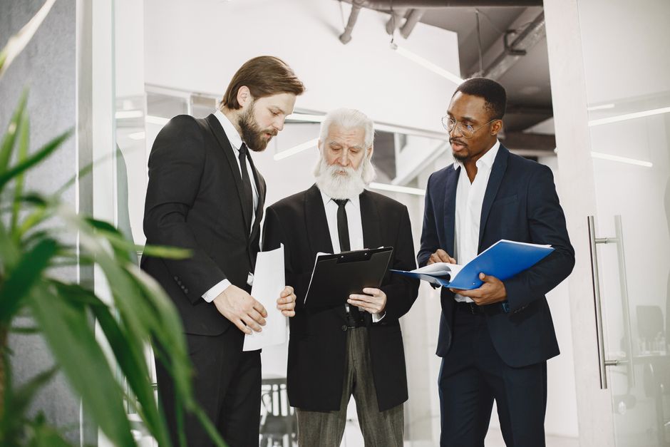 Diverse businessmen in professional attire discussing documents during an office meeting.