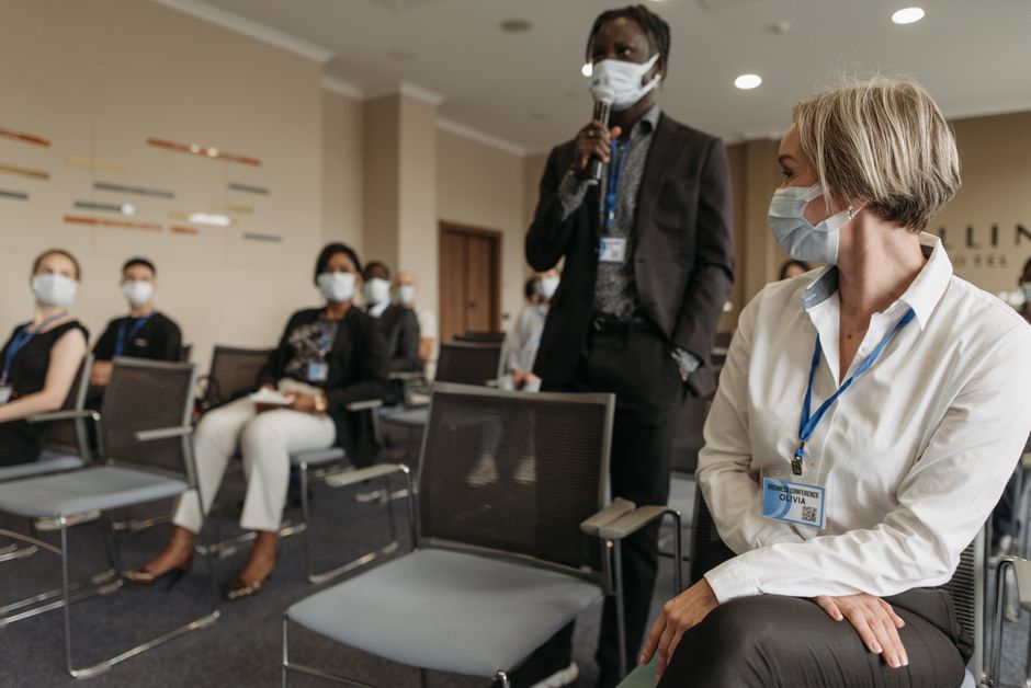 Diverse group of professionals in a business meeting wearing masks for safety.